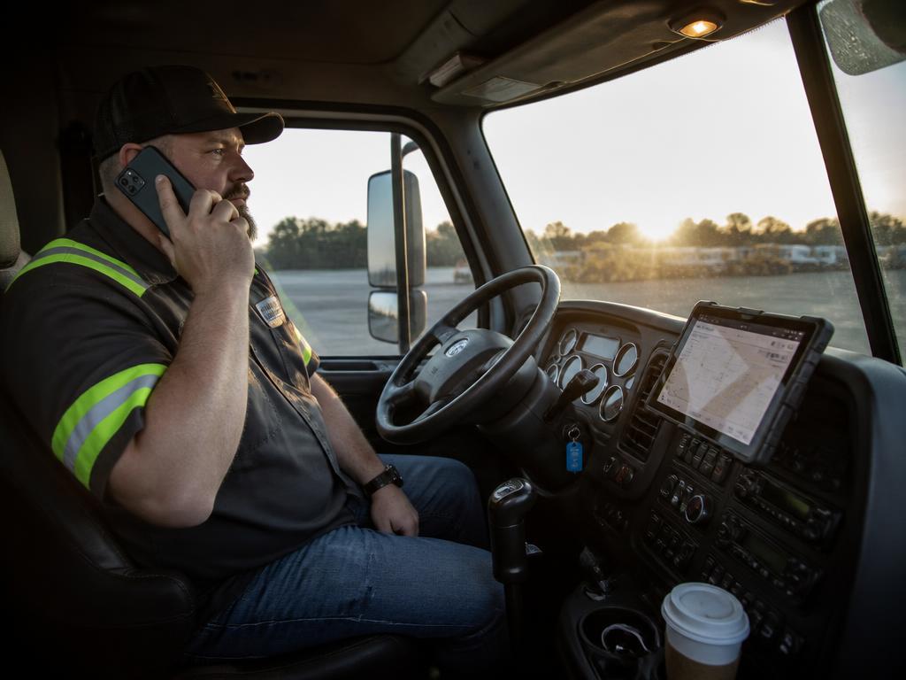 Tow truck owner taking a dispatch call from the cab of his truck at sunrise